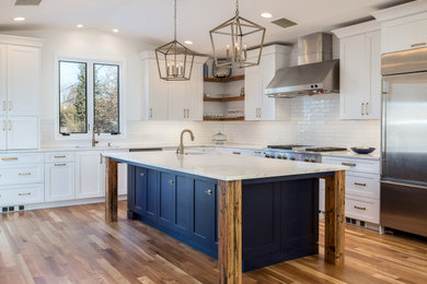 Example of a beach style brown floor and medium tone wood floor kitchen design in Denver with shaker cabinets, blue cabinets, quartzite countertops, white backsplash, stainless steel appliances, an island, white countertops, an undermount sink and subway tile backsplash