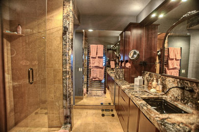 Large traditional master bathroom in Seattle with an undermount sink, flat-panel cabinets, medium wood cabinets, granite benchtops, a corner shower, brown tile, stone tile, grey walls and travertine floors.