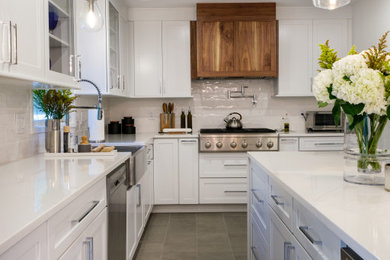 Mid-sized minimalist u-shaped porcelain tile and gray floor kitchen pantry photo in New York with a farmhouse sink, shaker cabinets, white cabinets, quartz countertops, white backsplash, porcelain backsplash, stainless steel appliances, an island and white countertops