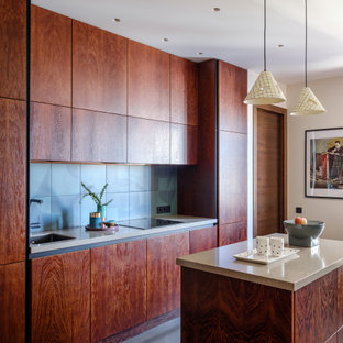 Новые идеи обустройства дома: маленькая параллельная кухня в современном стиле с плоскими фасадами, темными деревянными фасадами, столешницей из акрилового камня, фартуком из керамической плитки, полом из ламината, островом, черным полом, бежевой столешницей, врезной раковиной, синим фартуком и техникой под мебельный фасад