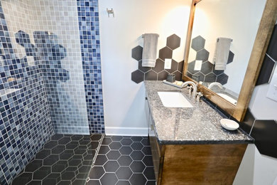 Small midcentury master bathroom in Raleigh with flat-panel cabinets, medium wood cabinets, a curbless shower, blue tile, ceramic tile, beige walls, ceramic floors, an undermount sink, granite benchtops, black floor, an open shower and blue benchtops.