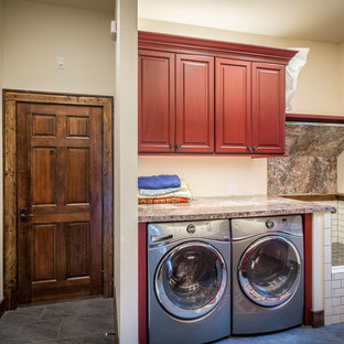 Expansive rustic galley utility room in Charlotte with a built-in sink, raised-panel cabinets, red cabinets, laminate countertops, beige walls, ceramic flooring and a side by side washer and dryer.