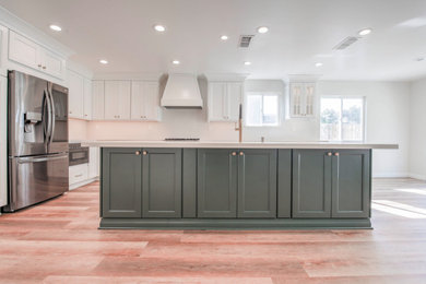 Design ideas for a large country eat-in kitchen in Sacramento with a farmhouse sink, shaker cabinets, green cabinets, quartz benchtops, white splashback, stone tile splashback, stainless steel appliances, vinyl floors, with island, brown floor and white benchtop.