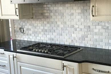 Example of a large classic l-shaped eat-in kitchen design in Other with raised-panel cabinets, white cabinets, quartzite countertops, gray backsplash, stone tile backsplash and an island