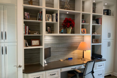 This is an example of a medium sized traditional study in DC Metro with beige walls, medium hardwood flooring, a built-in desk and brown floors.