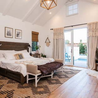 Inspiration pour une chambre parentale rustique avec un mur blanc, un sol en bois brun, un poêle à bois, un manteau de cheminée en métal et un sol beige.