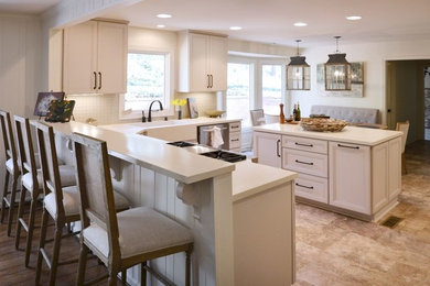 Inspiration for a large transitional l-shaped ceramic tile eat-in kitchen remodel in Birmingham with a farmhouse sink, white cabinets, white backsplash, ceramic backsplash, stainless steel appliances and an island