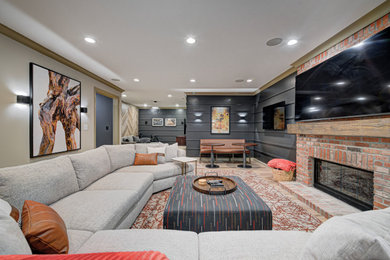 Design ideas for a mid-sized contemporary fully buried basement in Indianapolis with a standard fireplace, grey walls, light hardwood floors, a brick fireplace surround, brown floor and panelled walls.