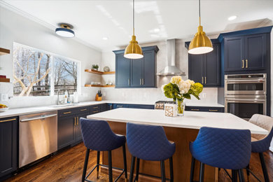 Mid-sized transitional l-shaped eat-in kitchen in DC Metro with an undermount sink, recessed-panel cabinets, blue cabinets, quartz benchtops, white splashback, ceramic splashback, stainless steel appliances, medium hardwood floors, with island, brown floor and white benchtop.