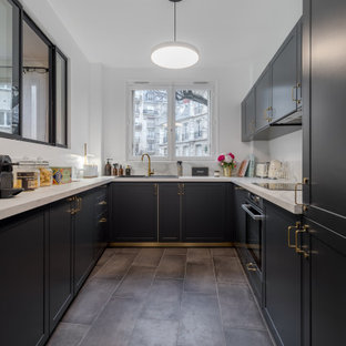 Idées déco pour une cuisine classique en U fermée et de taille moyenne avec un évier 1 bac, un placard avec porte à panneau encastré, des portes de placard noires, un plan de travail en stratifié, une crédence blanche, un sol en carrelage de céramique, un sol gris et un plan de travail blanc.