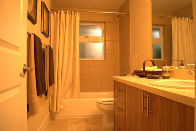 Bathroom - contemporary porcelain tile bathroom idea in Seattle with a drop-in sink, medium tone wood cabinets, quartz countertops and a two-piece toilet