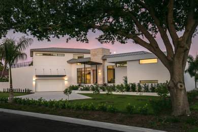 Example of a mid-sized trendy white two-story stucco exterior home design in Tampa with a metal roof