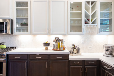 Example of a mid-sized minimalist single-wall ceramic tile and brown floor open concept kitchen design in Houston with a farmhouse sink, shaker cabinets, white cabinets, quartz countertops, white backsplash, marble backsplash, stainless steel appliances, an island and gray countertops