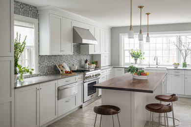 Inspiration for a transitional l-shaped gray floor kitchen remodel in Boston with a farmhouse sink, shaker cabinets, white cabinets, wood countertops, blue backsplash, porcelain backsplash, stainless steel appliances and an island