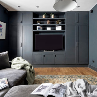 Immagine di un piccolo home theatre design con pareti grigie, parquet chiaro, TV a parete e pavimento marrone