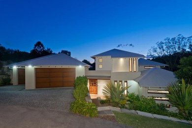 This is an example of a large contemporary two-storey beige house exterior in Brisbane with concrete fiberboard siding, a hip roof and a metal roof.