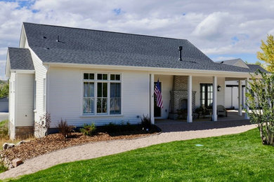 This is an example of a mid-sized traditional one-storey white house exterior in Denver with vinyl siding, a gable roof and a shingle roof.