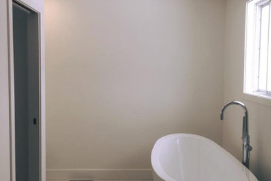 Example of a mid-sized minimalist ceramic tile and beige floor freestanding bathtub design in Other with beige walls