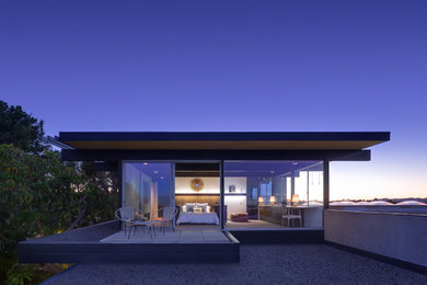 Inspiration for a modern two-storey glass house exterior in Los Angeles with a flat roof.