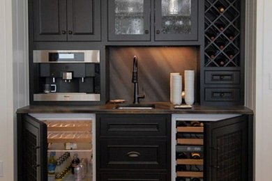 This is an example of a small traditional single-wall wet bar in Orlando with an undermount sink, recessed-panel cabinets, black cabinets, laminate benchtops, multi-coloured splashback and medium hardwood floors.