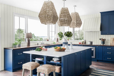 Example of a large french country u-shaped dark wood floor and brown floor open concept kitchen design in Other with a drop-in sink, beaded inset cabinets, blue cabinets, quartzite countertops, white backsplash, shiplap backsplash, stainless steel appliances, an island and white countertops