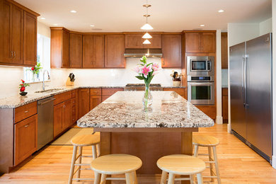 Inspiration for a large timeless u-shaped medium tone wood floor and brown floor eat-in kitchen remodel in Vancouver with a double-bowl sink, shaker cabinets, medium tone wood cabinets, granite countertops, white backsplash, subway tile backsplash, stainless steel appliances and an island