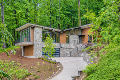 Example of a large trendy two-story stone house exterior design in Other with a butterfly roof, a metal roof and a black roof