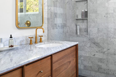 Example of a mid-sized transitional master multicolored tile and marble tile porcelain tile, black floor and double-sink bathroom design in Los Angeles with flat-panel cabinets, medium tone wood cabinets, a wall-mount toilet, white walls, an undermount sink, marble countertops, a hinged shower door, multicolored countertops and a freestanding vanity