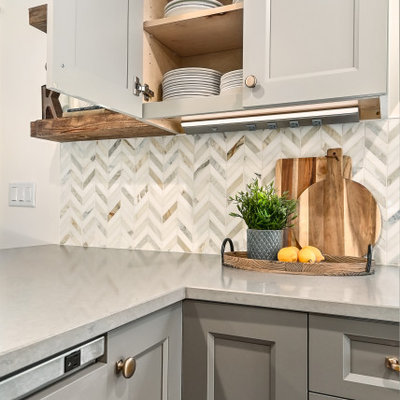 Example of a huge country l-shaped medium tone wood floor and brown floor eat-in kitchen design in Milwaukee with a farmhouse sink, shaker cabinets, gray cabinets, quartz countertops, white backsplash, marble backsplash, stainless steel appliances, an island and gray countertops