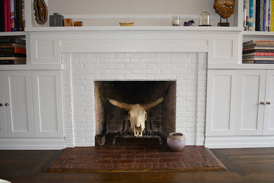 Living room - transitional dark wood floor and brown floor living room idea in New York with beige walls, a standard fireplace, a wood fireplace surround and a concealed tv