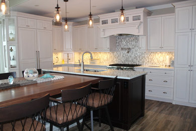 Example of a large classic l-shaped kitchen design in Other with raised-panel cabinets, white cabinets, quartz countertops and an island