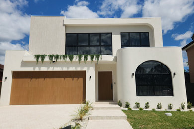 Inspiration for a mid-sized mediterranean two-storey brick white house exterior in Sydney with a flat roof, a metal roof and a white roof.