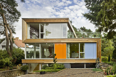 Inspiration for a modern three-storey brown exterior in Berlin with wood siding and a flat roof.