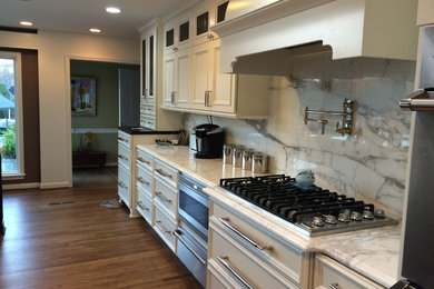 Transitional single-wall medium tone wood floor enclosed kitchen photo in DC Metro with a farmhouse sink, recessed-panel cabinets, white cabinets, wood countertops, white backsplash, stone slab backsplash, stainless steel appliances and an island
