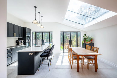 Design ideas for a small modern single-wall open plan kitchen in London with a double-bowl sink, shaker cabinets, black cabinets, quartz worktops, integrated appliances, medium hardwood flooring, an island, brown floors and multicoloured worktops.