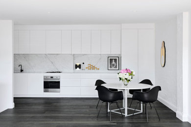 Design ideas for a contemporary l-shaped open plan kitchen in London with an undermount sink, flat-panel cabinets, white cabinets, marble benchtops, white splashback, panelled appliances, dark hardwood floors, brown floor and white benchtop.