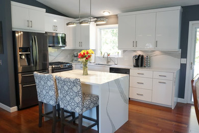 Example of a mid-sized trendy l-shaped dark wood floor and red floor eat-in kitchen design in Providence with an undermount sink, flat-panel cabinets, white cabinets, quartz countertops, white backsplash, stone slab backsplash, stainless steel appliances, an island and white countertops