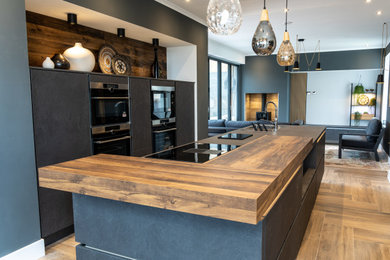 Inspiration for a large contemporary galley open plan kitchen in Other with a built-in sink, flat-panel cabinets, grey cabinets, laminate countertops, stainless steel appliances, plywood flooring, an island, grey worktops and feature lighting.