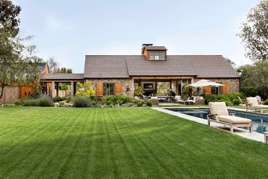 Large country one-storey grey house exterior in Los Angeles with stone veneer, a shingle roof and a gable roof.
