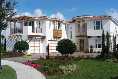 This is an example of a large mediterranean two-storey stucco white house exterior in Orlando with a tile roof.