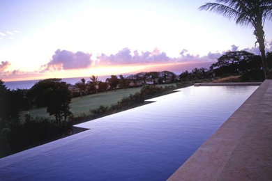 Photo of a tropical backyard rectangular infinity pool in Hawaii with concrete pavers.
