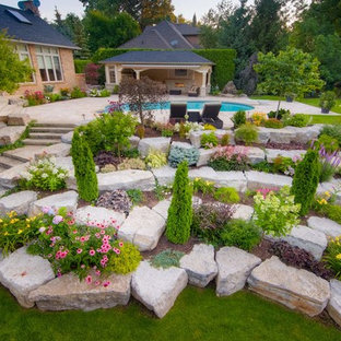 Aménagement d'un très grand jardin classique l'été avec une pente, une colline ou un talus, une exposition ensoleillée, des pavés en pierre naturelle et pierres et graviers.