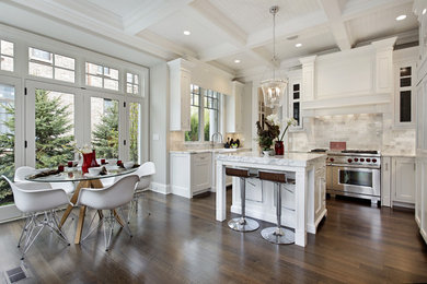 Example of a large transitional u-shaped dark wood floor and brown floor open concept kitchen design in Other with a farmhouse sink, shaker cabinets, white cabinets, quartzite countertops, white backsplash, subway tile backsplash, paneled appliances, an island and white countertops