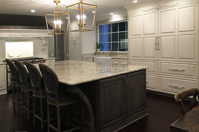 Large cottage l-shaped dark wood floor and brown floor eat-in kitchen photo in Cleveland with a farmhouse sink, white cabinets, granite countertops, gray backsplash, subway tile backsplash, stainless steel appliances, an island and raised-panel cabinets