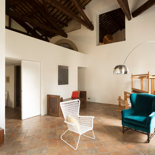 Großes, Fernseherloses Landhaus Wohnzimmer im Loft-Stil mit weißer Wandfarbe, Terrakottaboden, Kamin, Kaminumrandung aus Stein und rosa Boden in Sonstige