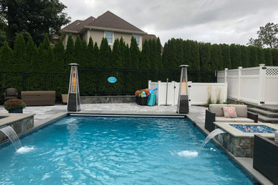 Example of a minimalist backyard concrete paver and rectangular natural hot tub design