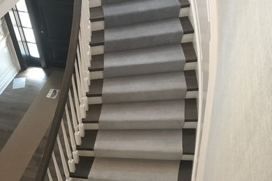 Modelo de escalera curva tradicional grande con escalones de madera, contrahuellas de madera pintada y barandilla de madera