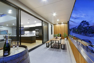 Inspiration for a mid-sized modern balcony in Melbourne with a roof extension and glass railing.