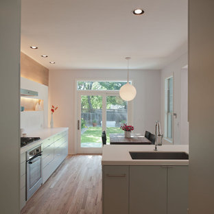 Ejemplo de cocina comedor minimalista con fregadero de un seno, armarios con paneles lisos, puertas de armario verdes, encimera de cuarzo compacto, salpicadero blanco y salpicadero de losas de piedra