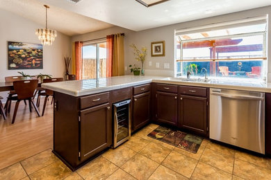 Inspiration for a mid-sized eclectic u-shaped cement tile floor and multicolored floor eat-in kitchen remodel in Los Angeles with an undermount sink, recessed-panel cabinets, brown cabinets, tile countertops, yellow backsplash, porcelain backsplash, stainless steel appliances, a peninsula and white countertops